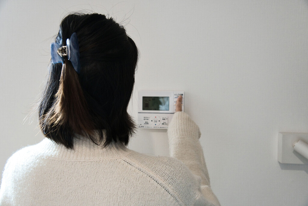 給湯器のリモコンを操作する女性